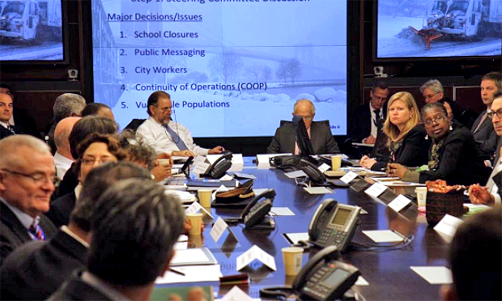 people sitting around a conference table with projection of data behind them