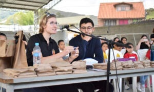 woman and man talking to group outdoors under a tent