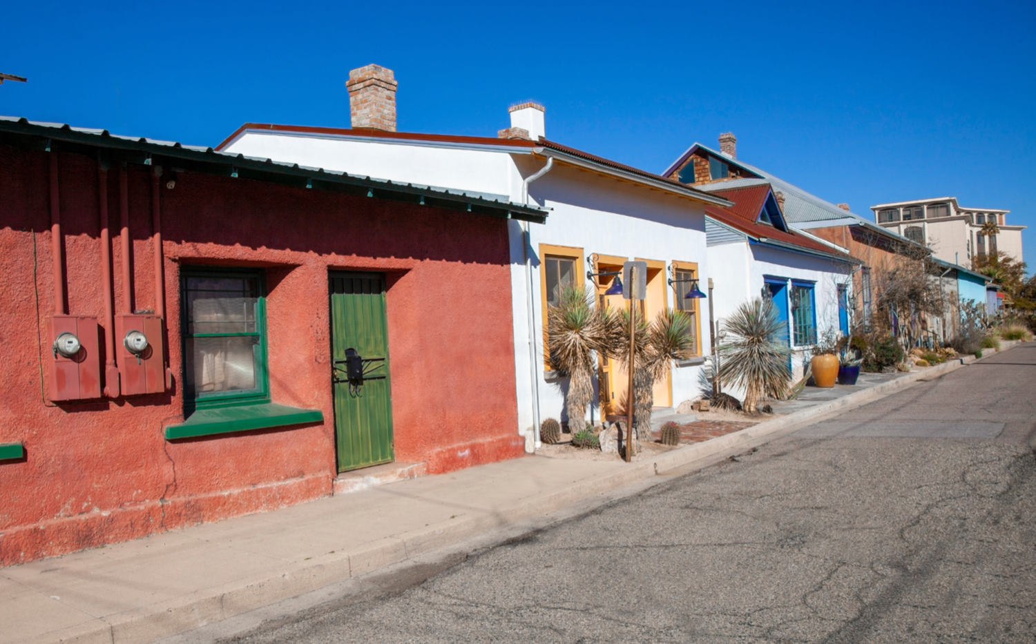 Colorful adobe homes line a sunlit street in Tucson’s historic Barrio Viejo district.